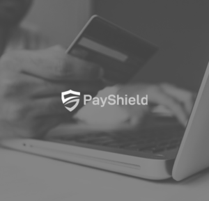 The PayShield logo on top of a person using a laptop and holding a payment card.