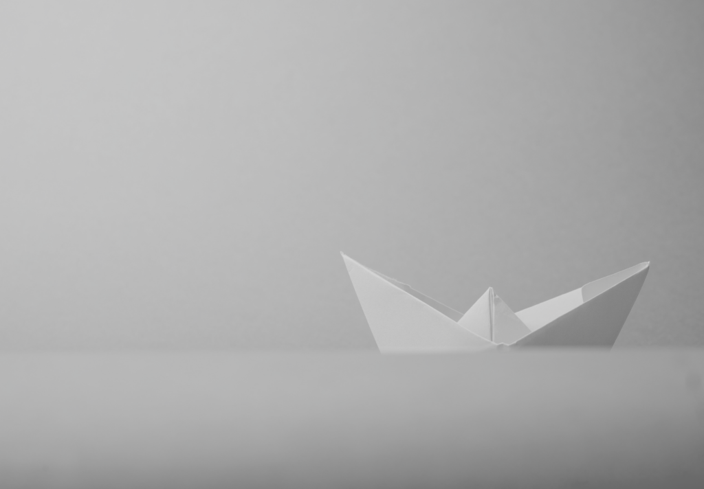 A greyscale image of a paper boat.